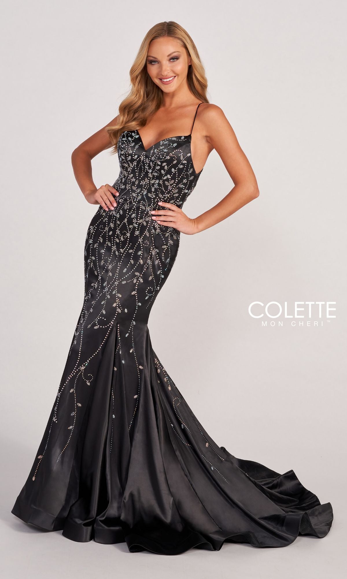 A woman poses in the Colette CL2043 Keyhole-Back Long Satin Prom Dress, a fitted, floor-length gown with thin straps and a slight train that elegantly highlights her silhouette against a plain background.